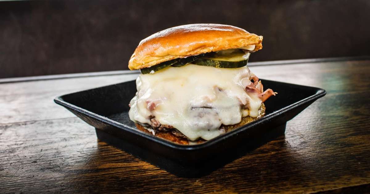A cheeseburger on a black plate from Ball Ground Burger Bus