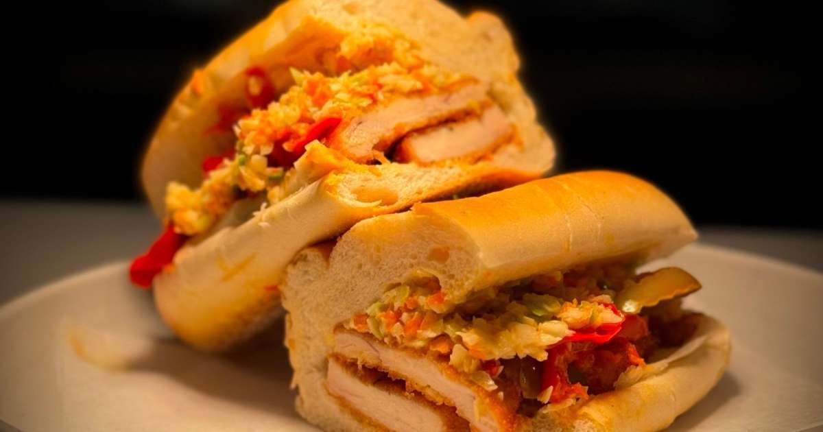 A chicken sandwich from POPS on a plate in front of a dark background