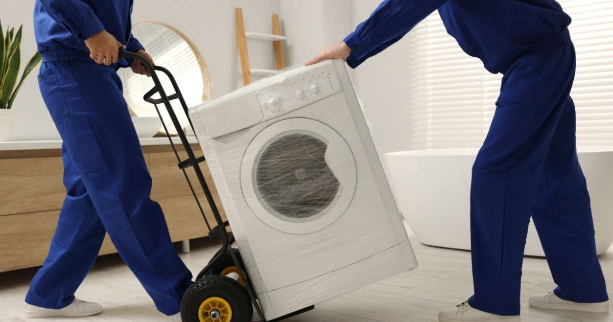 Two Nelson movers carefully moving an appliance on a dolly. 