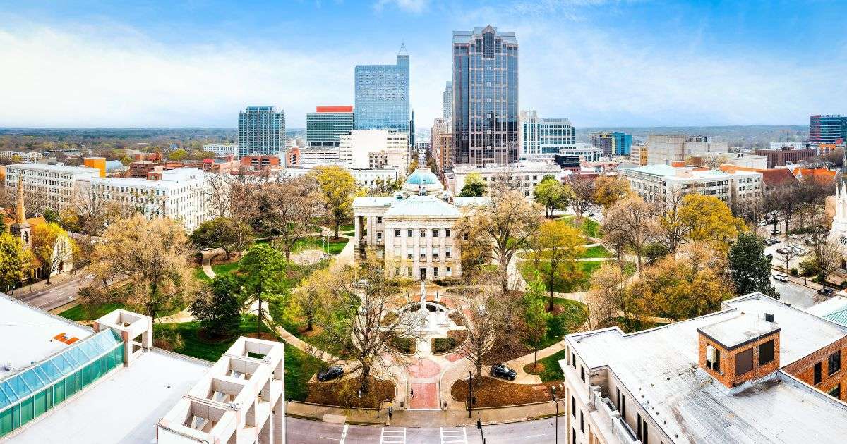 Panorama of the North Carolina State Capitol and Raleigh skyline under a clear, blue sky