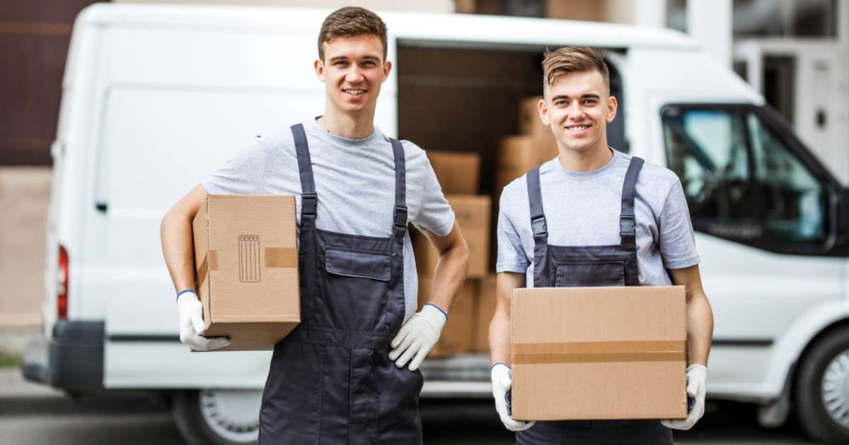 Two movers in Clermont GA holding boxes beside a moving truck