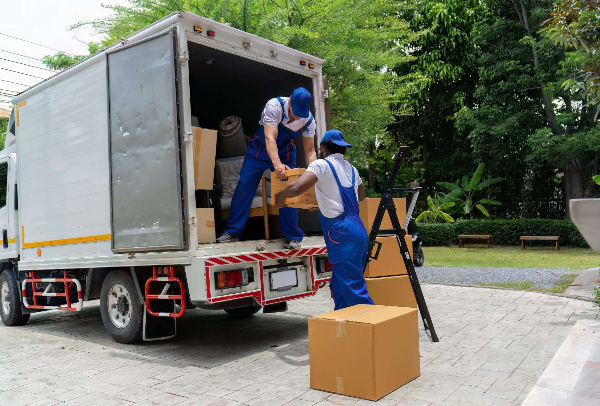 Senoia movers in blue overalls loading boxes into the back of a truck 