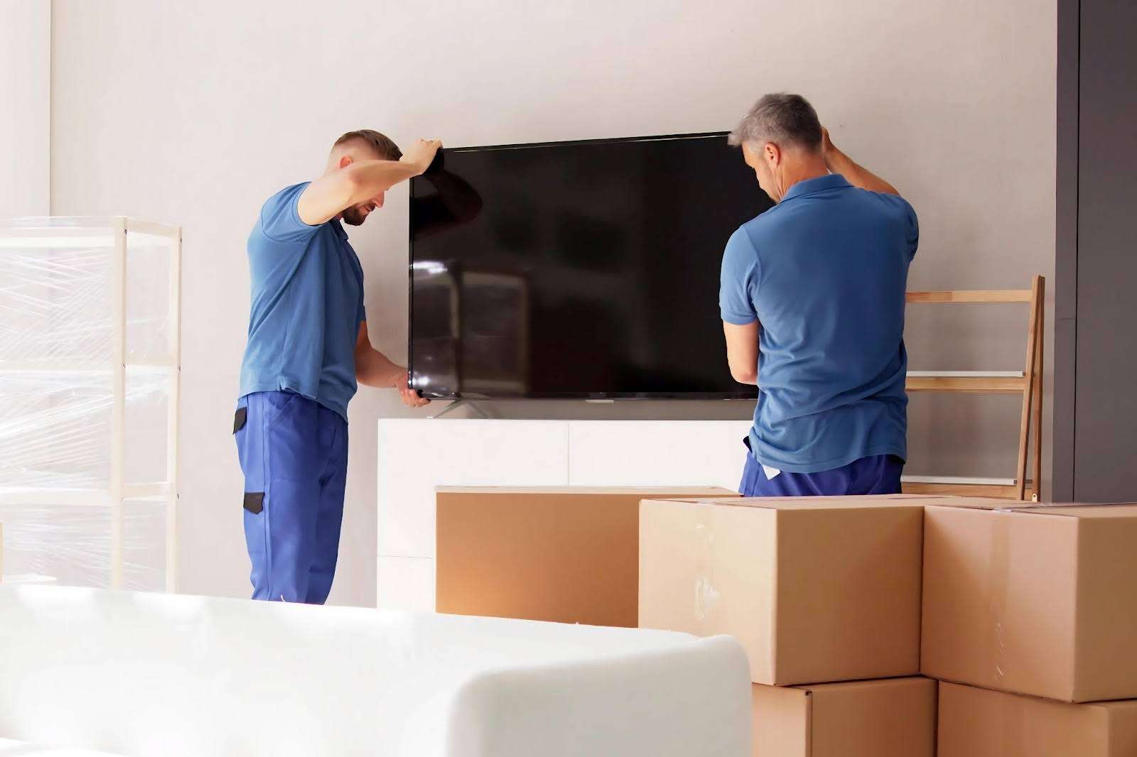two Flowery Branch movers removing a television from a TV stand