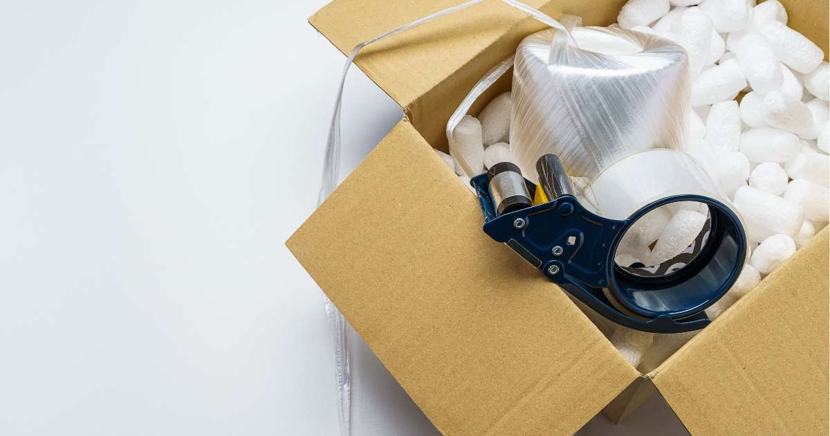 Box with packing peanuts, tape, and other packing supplies.