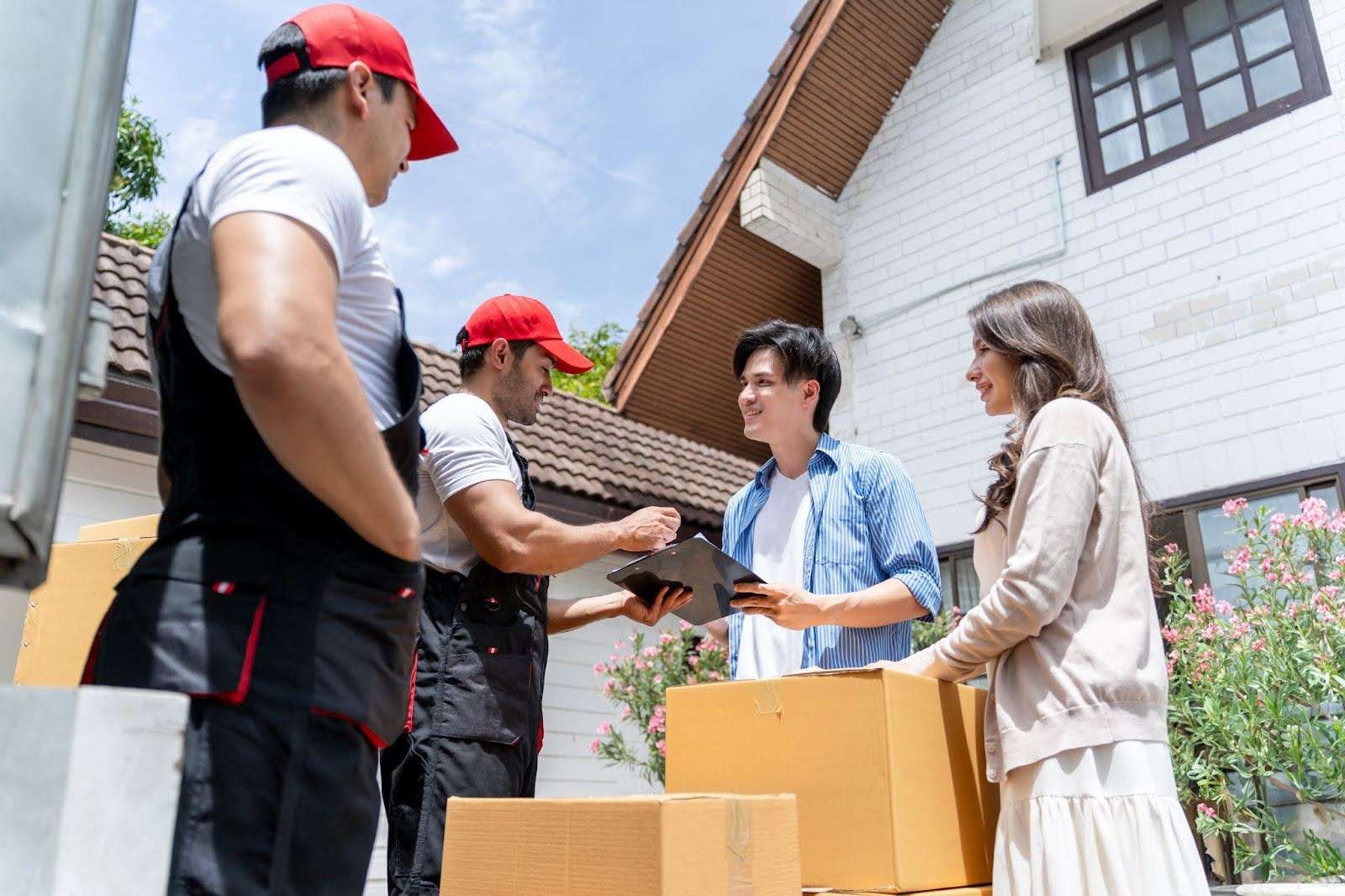 Young couple and two Temple GA movers talking, smiling, and signing papers.
