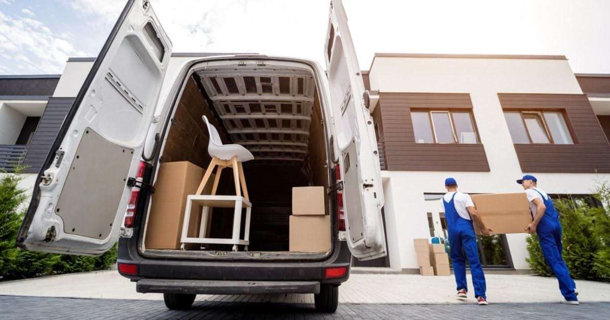 Two movers in Bremen moving a cardboard box out of a packed moving truck