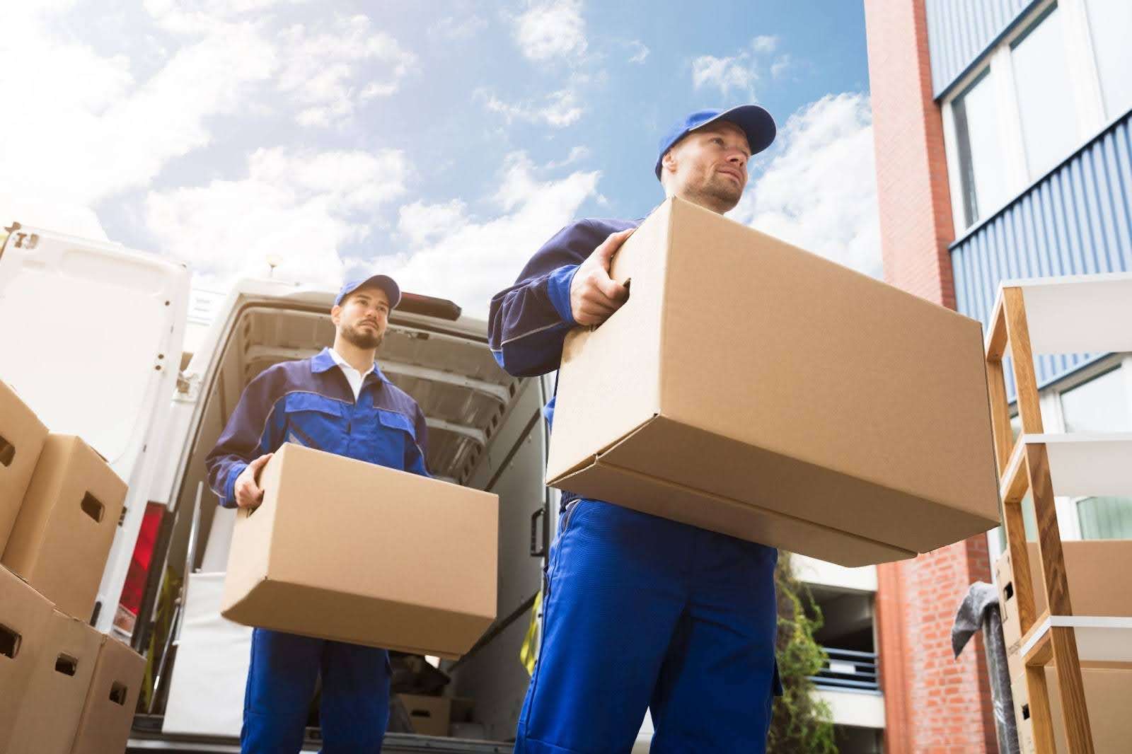 two Carrollton GA movers in dressed in blue carrying boxes out of a moving van