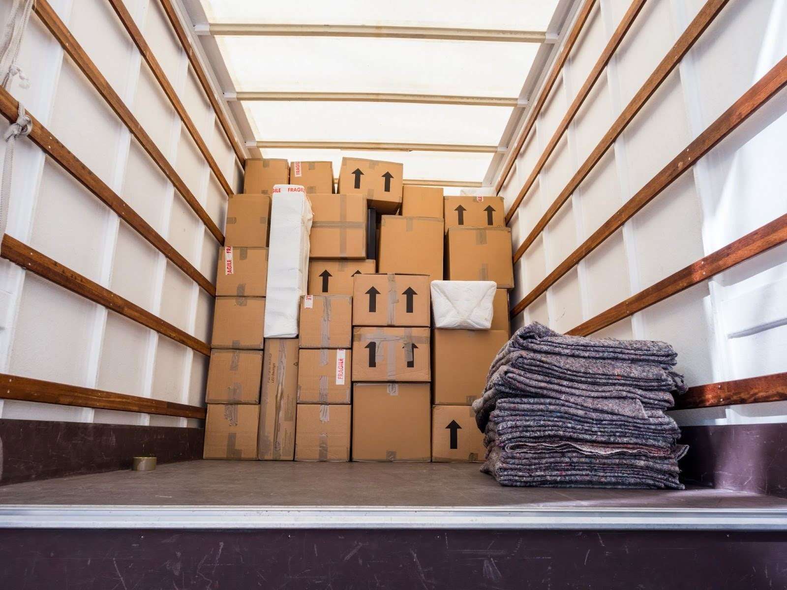 Boxes and moving blankets sitting in the back of a moving truck.